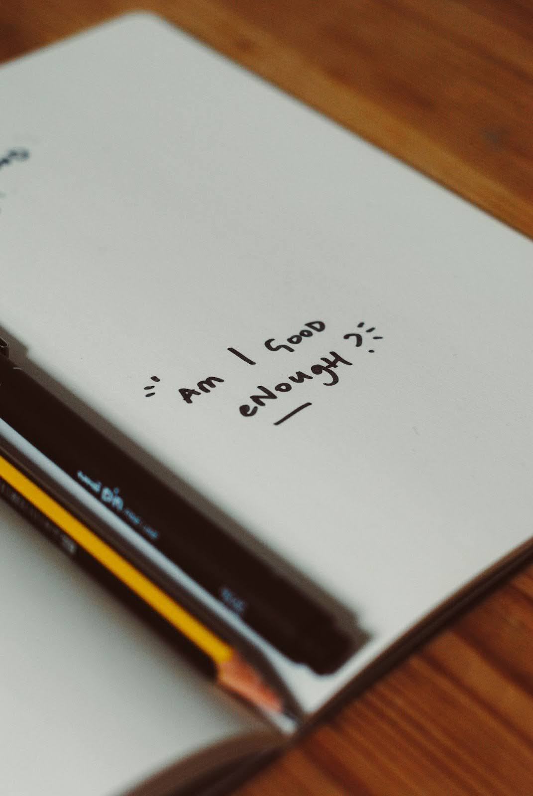 Notebook with handwritten text "Am I good enough?", challenging Negative Beliefs
