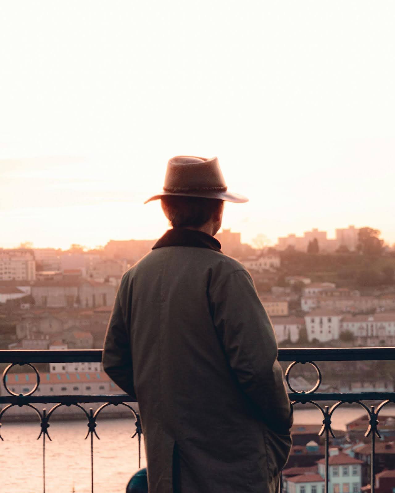 Man in trench coat gazes at river, symbolizing self-discovery.
