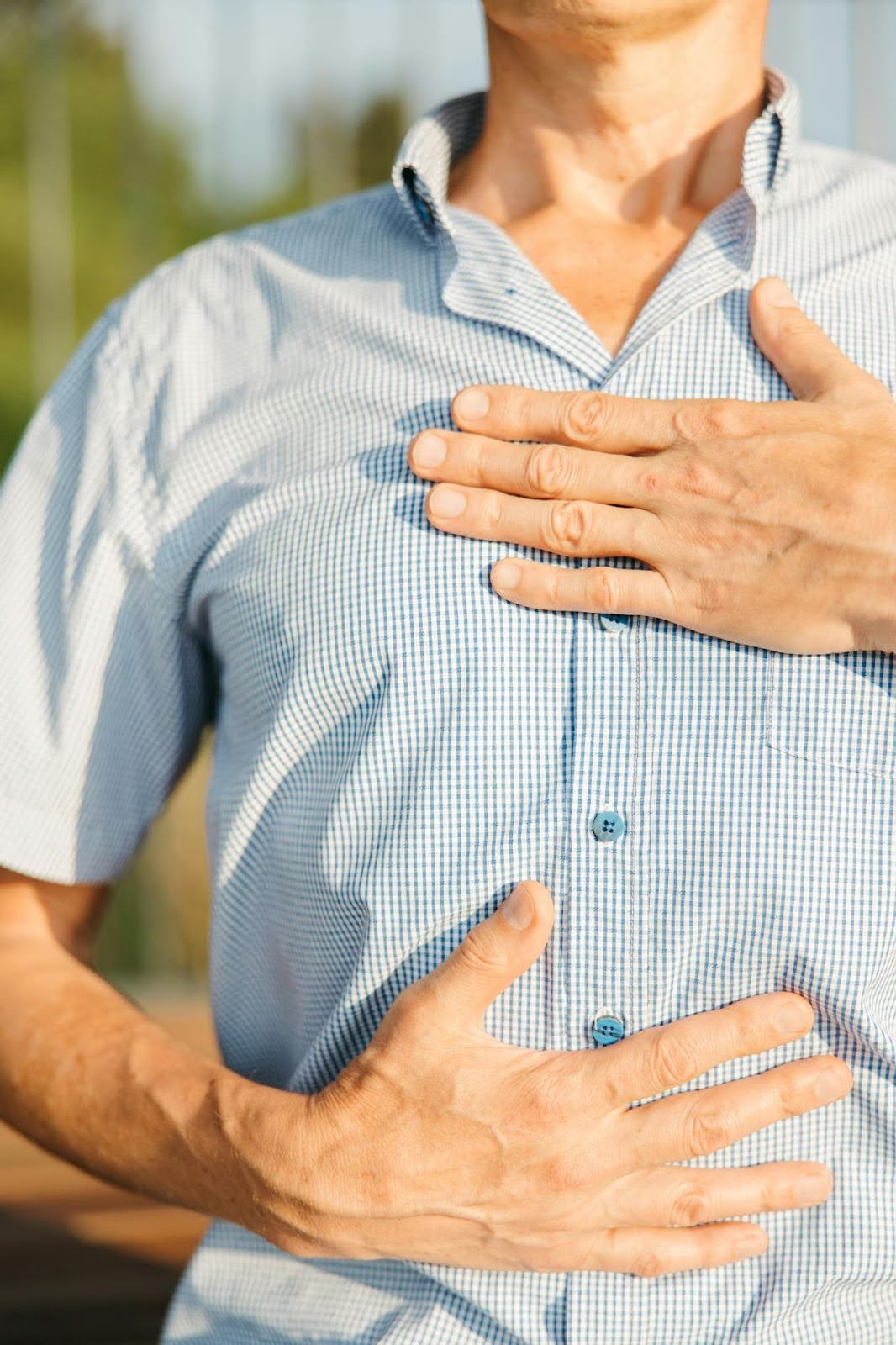 Man with his hands on heart and stomach, illustrate listening to your body sensations.
