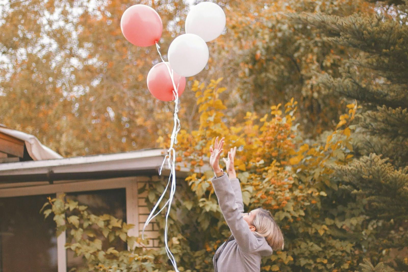 Girl releasing balloons with hands in the air, symbolizing the release of anger and stress