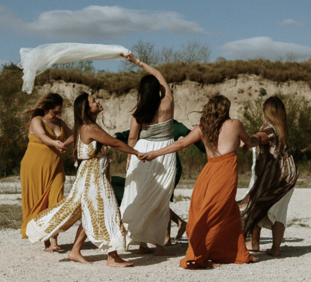 Women holding hands in nature, embracing sisterhood and feminine empowerment during a Tantra retreat.