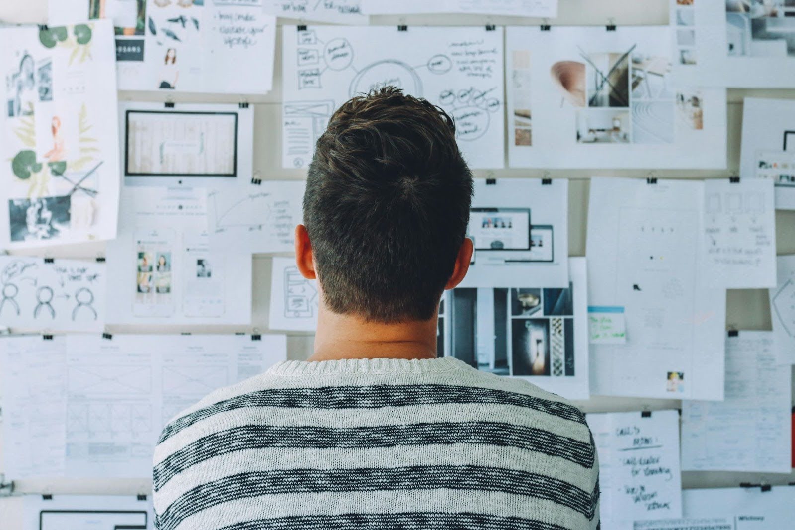 Man looks at research board, representing decision-making  in personal growth journey.