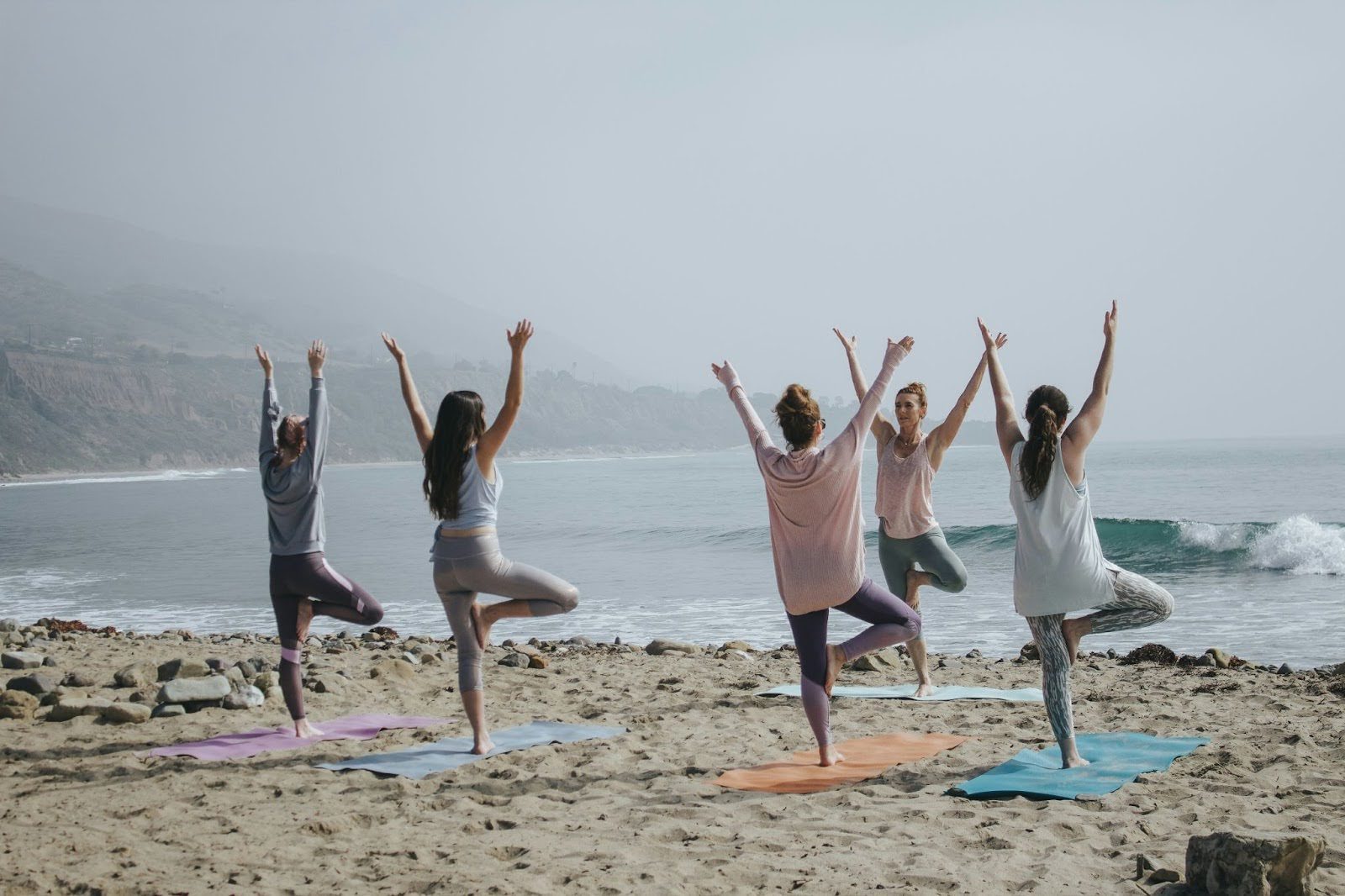 People do yoga on beach, showcasing relaxation and mindfulness activities .