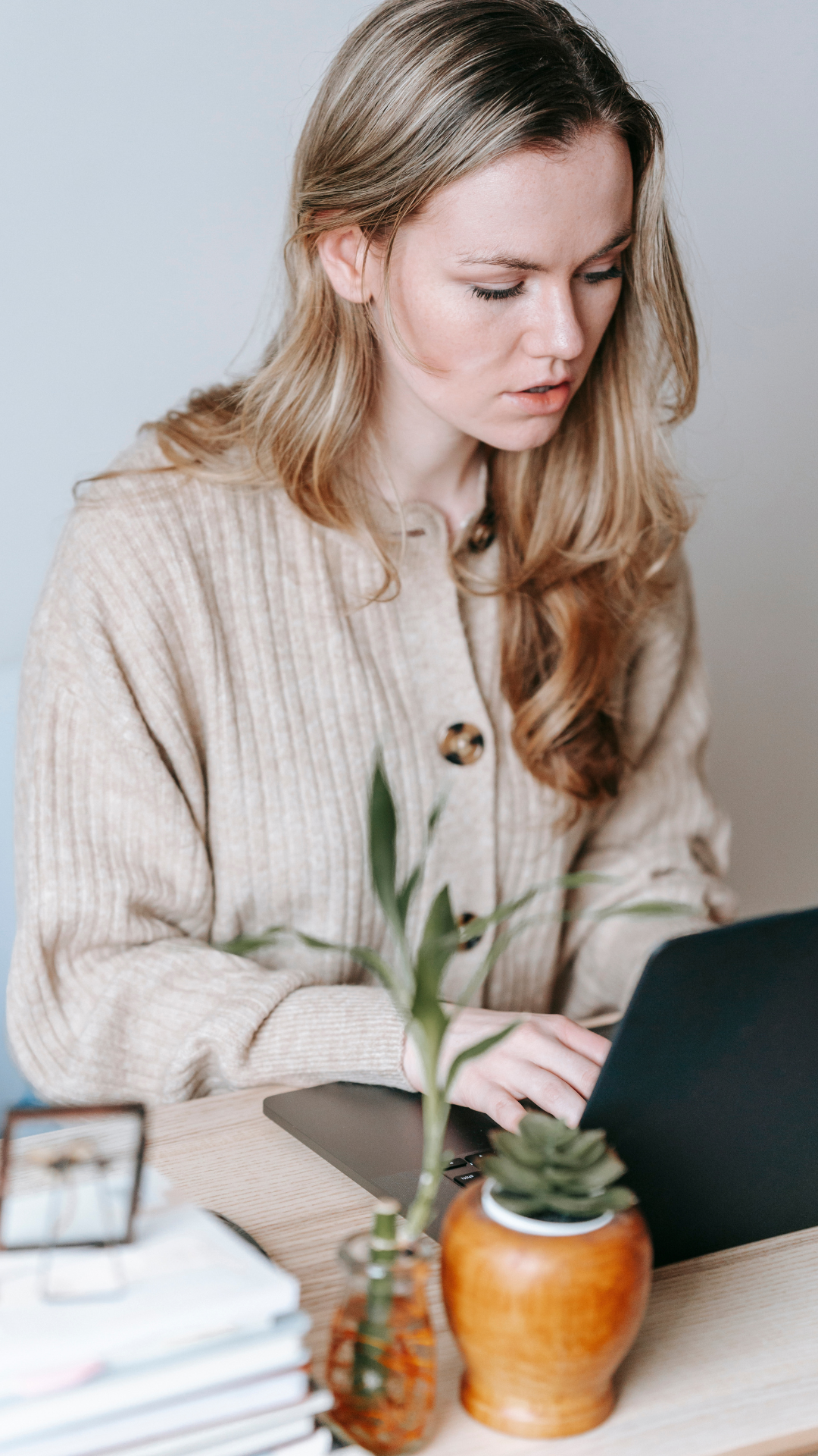 Focused woman working on a laptop at a minimalist desk, representing calm, intentional business building