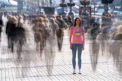 Young woman stands in middle of crowd of blurry people.