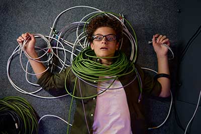 Frustrated overwhelmed IT engineer tangles in wires