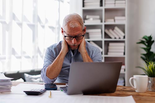 Sad gray haird architect senior man working on laptop