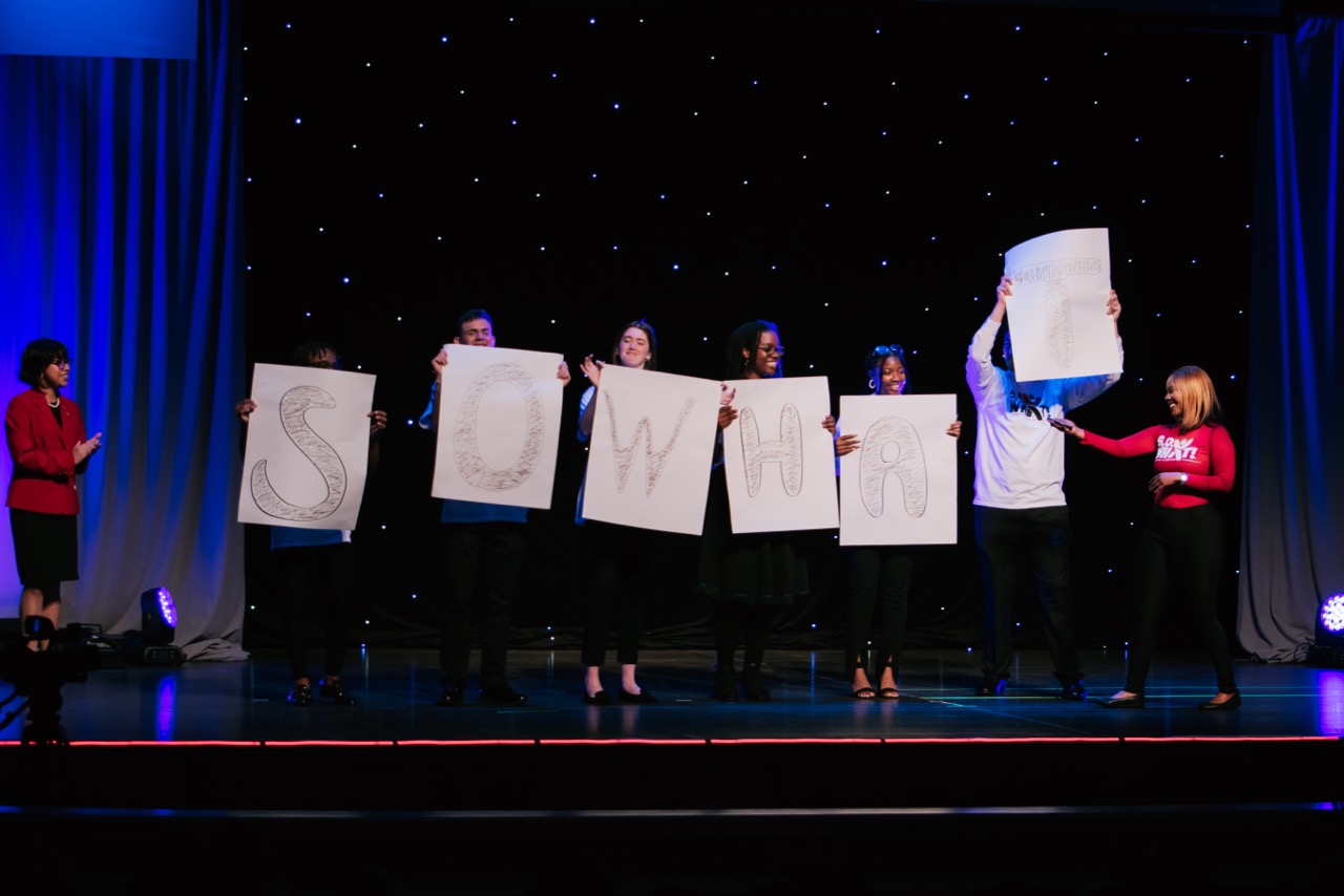 students holding so what signs