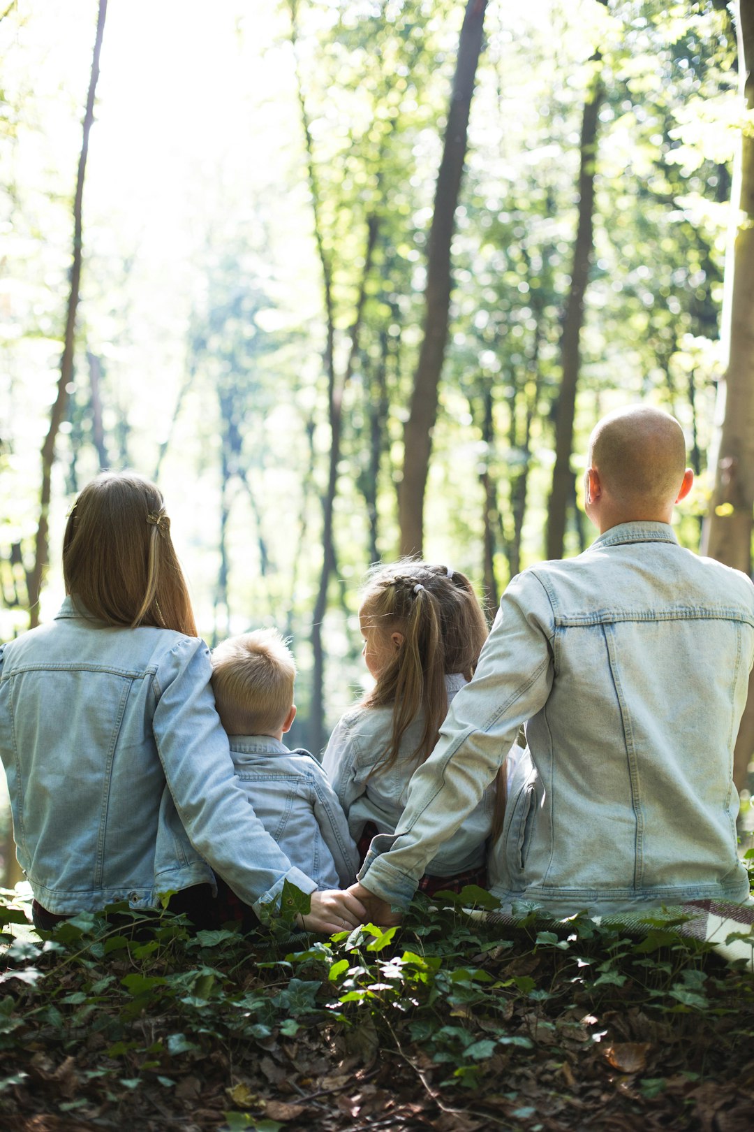 family of four sitting in a forest