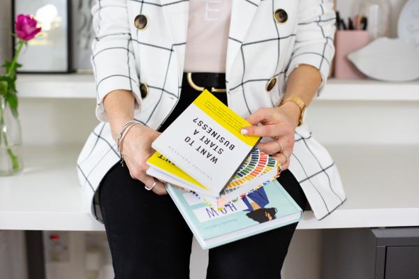Emmeline holding books sat on a desk 