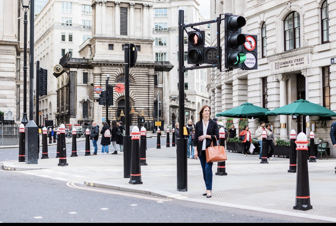 A female in her forties waiting to cross a road in a busy street in London