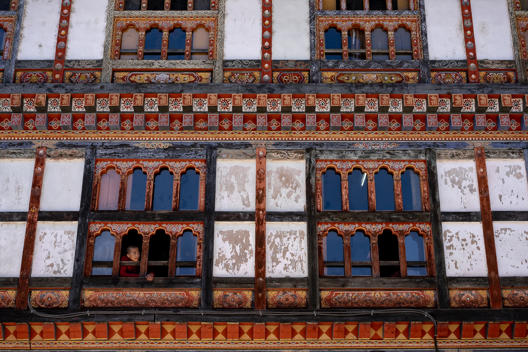 Intricate details of traditional Bhutanese monastery architecture, windows and facade - Raw Tours.