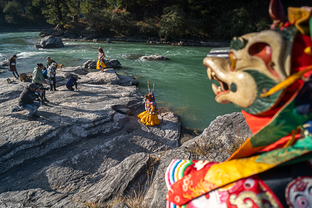 Colorful dancers performing in a circle at Bhutanese outdoor festival - photographed with Raw Tours.