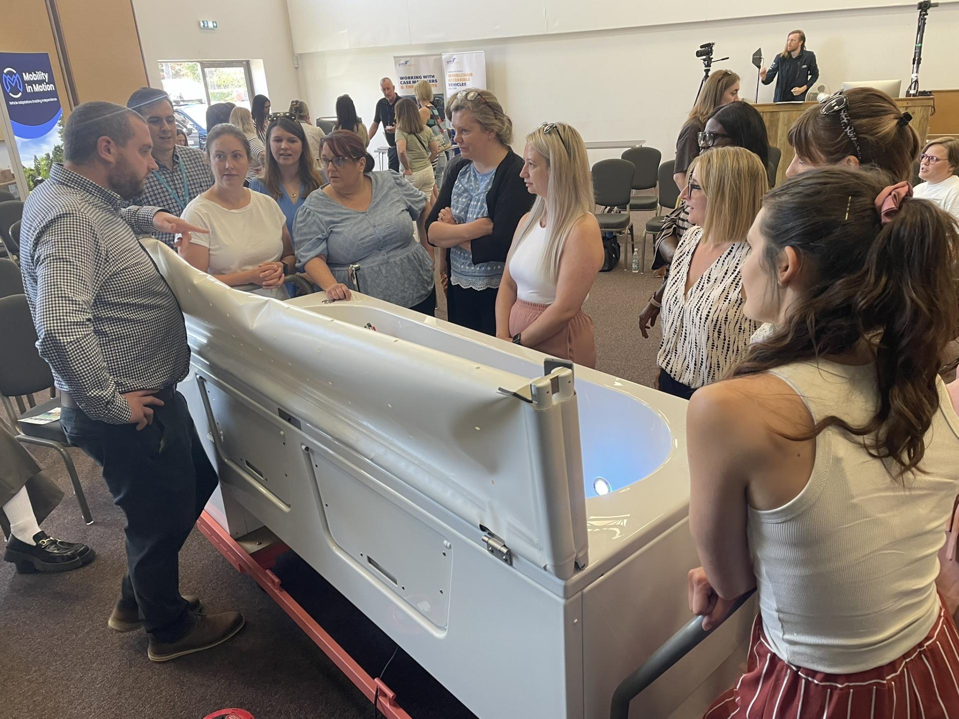 Young man sitting in an office and delivering a webinar. He has his laptop open and is waving at zoom participants.