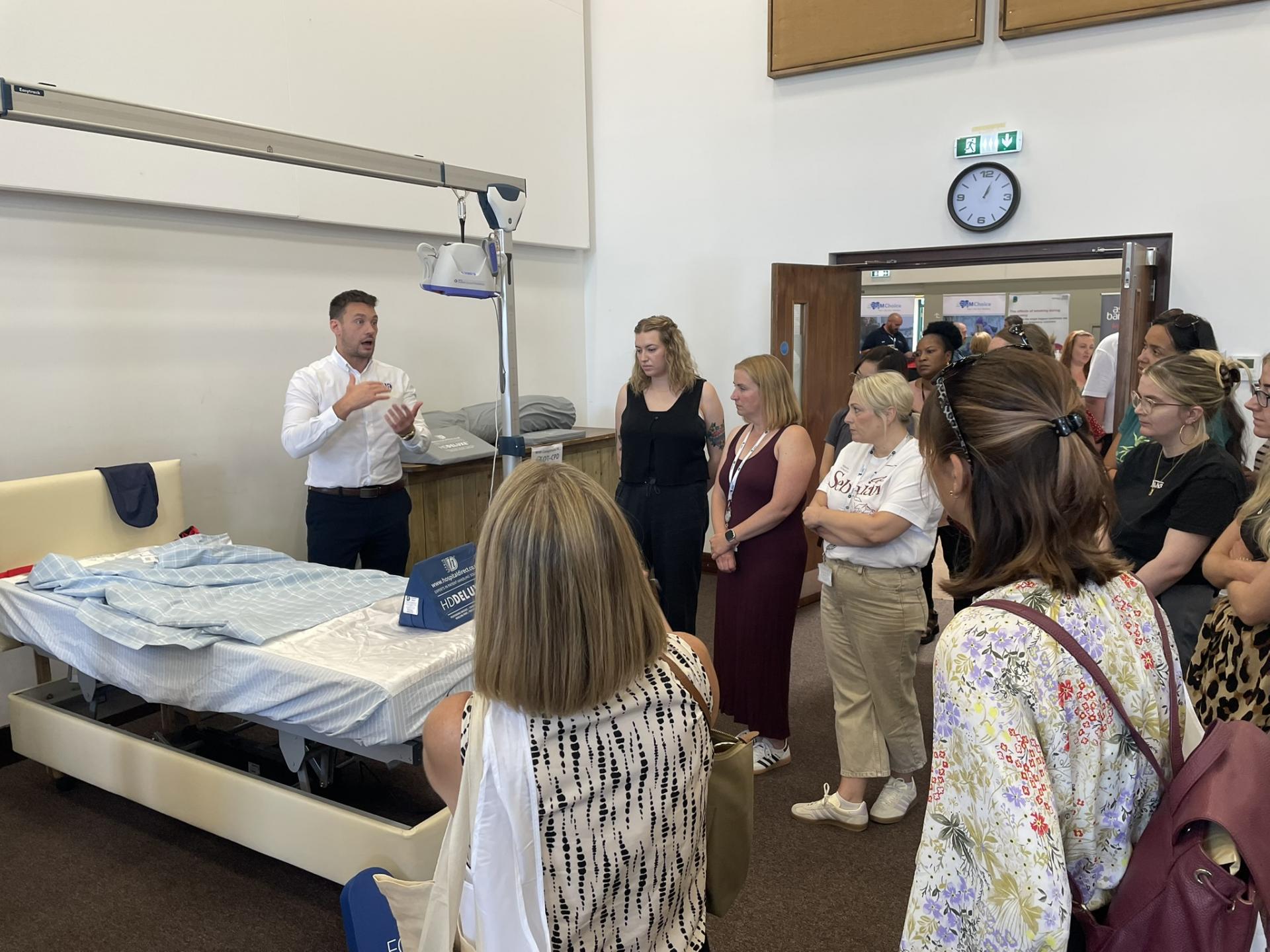 Young man sitting in an office and delivering a webinar. He has his laptop open and is waving at zoom participants.