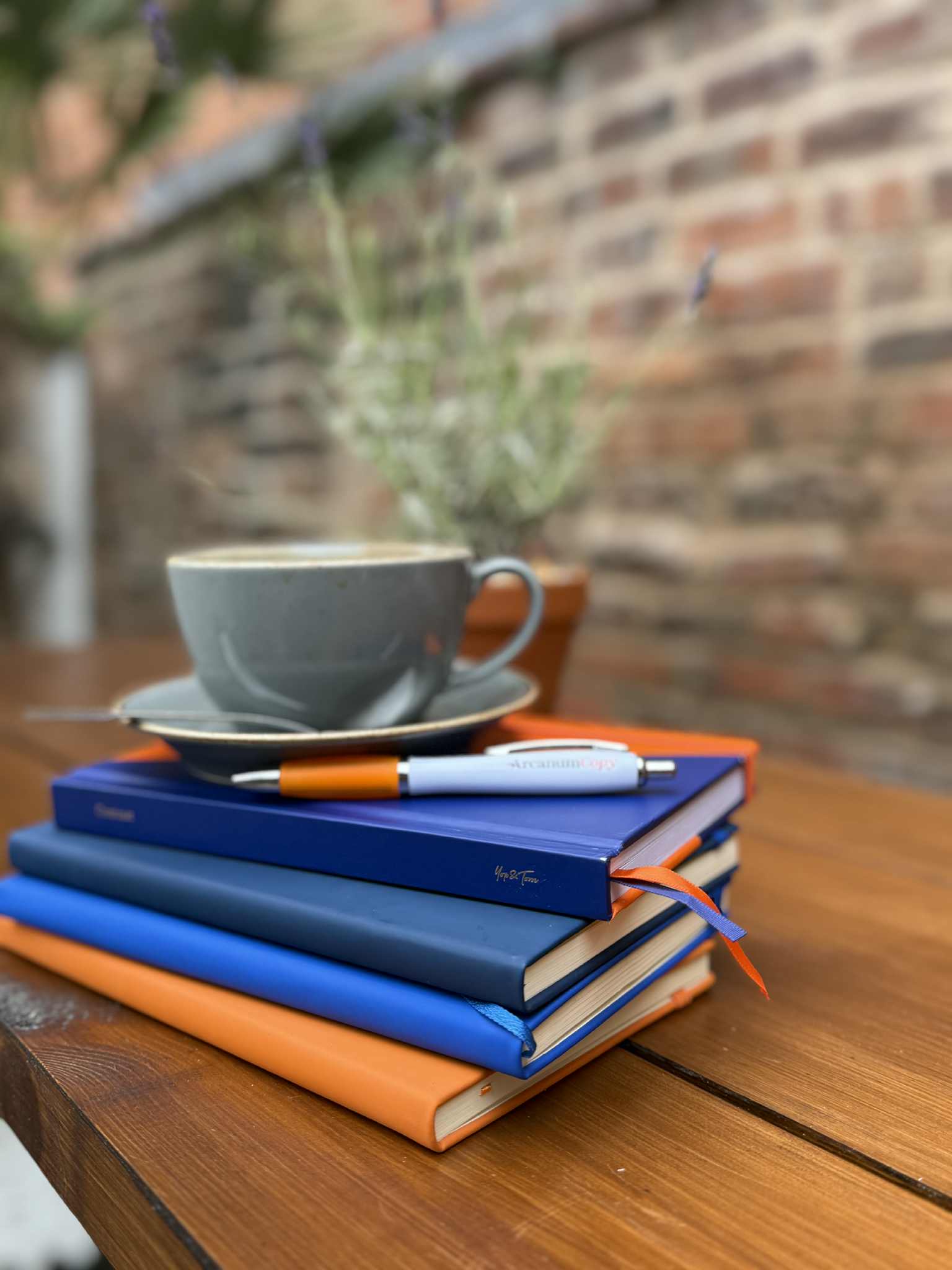 A coffee cup on top of a stack of blue and orange books.